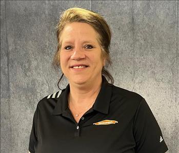 Female employee wearing black shirt standing in front of grey backdrop