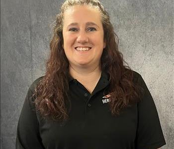 Female standing in front of grey background wearing a black SERVPRO shirt