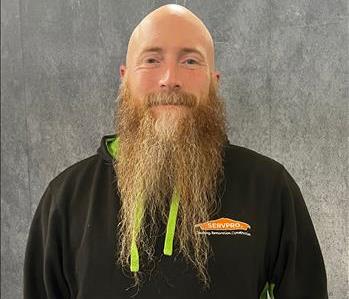 Male employee with long beard standing in front of grey backdrop