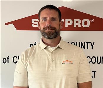 Male employee wearing white SERVPRO shirt standing in front of SERVPRO sign